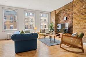 A modern living room with a blue sofa, a wooden rocking chair, and a television. - Trendy Shoreditch Pad, 5 Min Walk to Old Street (London)