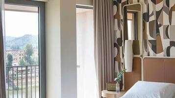 Ett hotellrum med en stor säng, en balkong och en vägg med ett mönster.