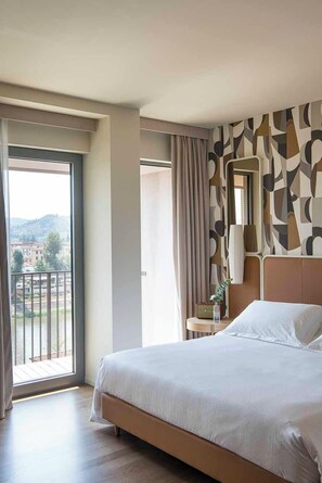 A hotel room with a large bed, a balcony, and a patterned wall. - Columbus Urban Resort (Florence)