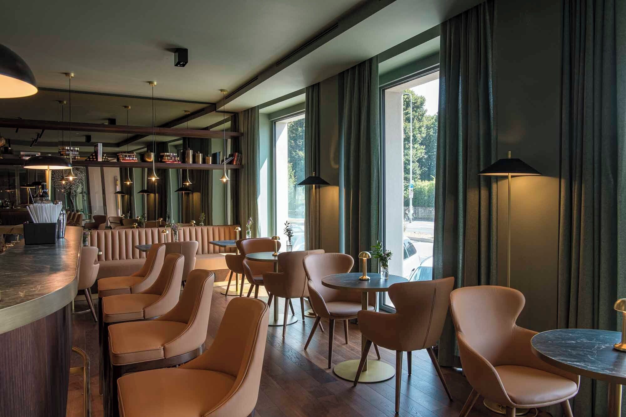 A modern bar area with leather seating, pendant lighting, and large windows offering a view of the outdoors.