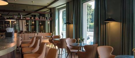 A modern bar area with leather seating, pendant lighting, and large windows offering a view of the outdoors.
