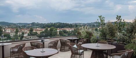 A rooftop terrace with wicker furniture and a view of a town.