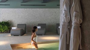 A spa area with a pool, two lounge chairs, and a statue. - Columbus Urban Resort (Florence)