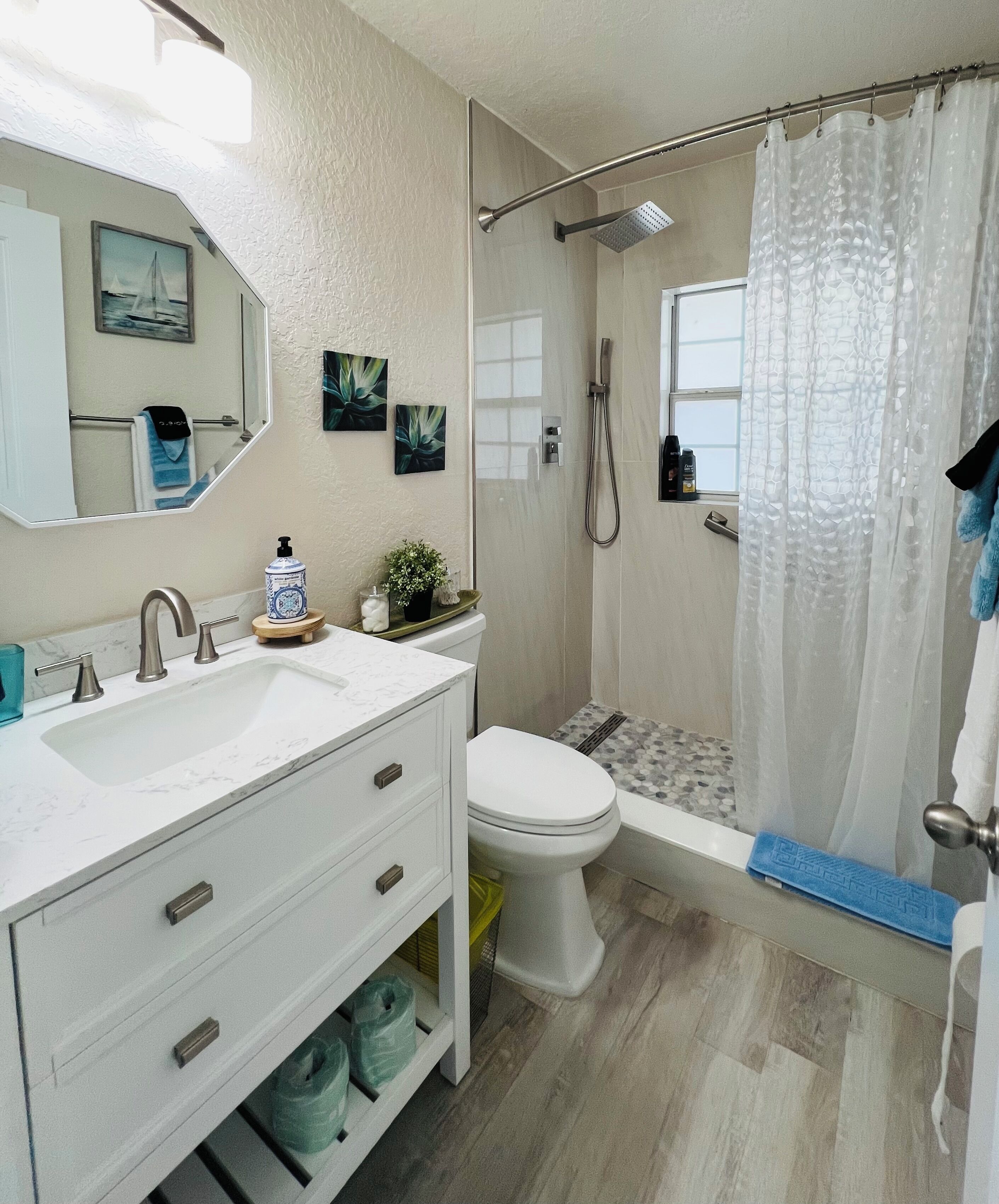 Une salle de bain équipée d’un lavabo, d’un miroir, de toilettes, d’une douche et d’une fenêtre.