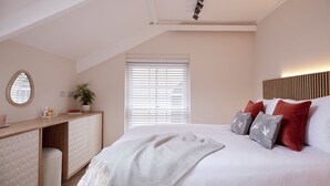 A bedroom with a bed, bedside table, and a window with blinds. - Coach House Totnes: Natural Luxe (Totnes)