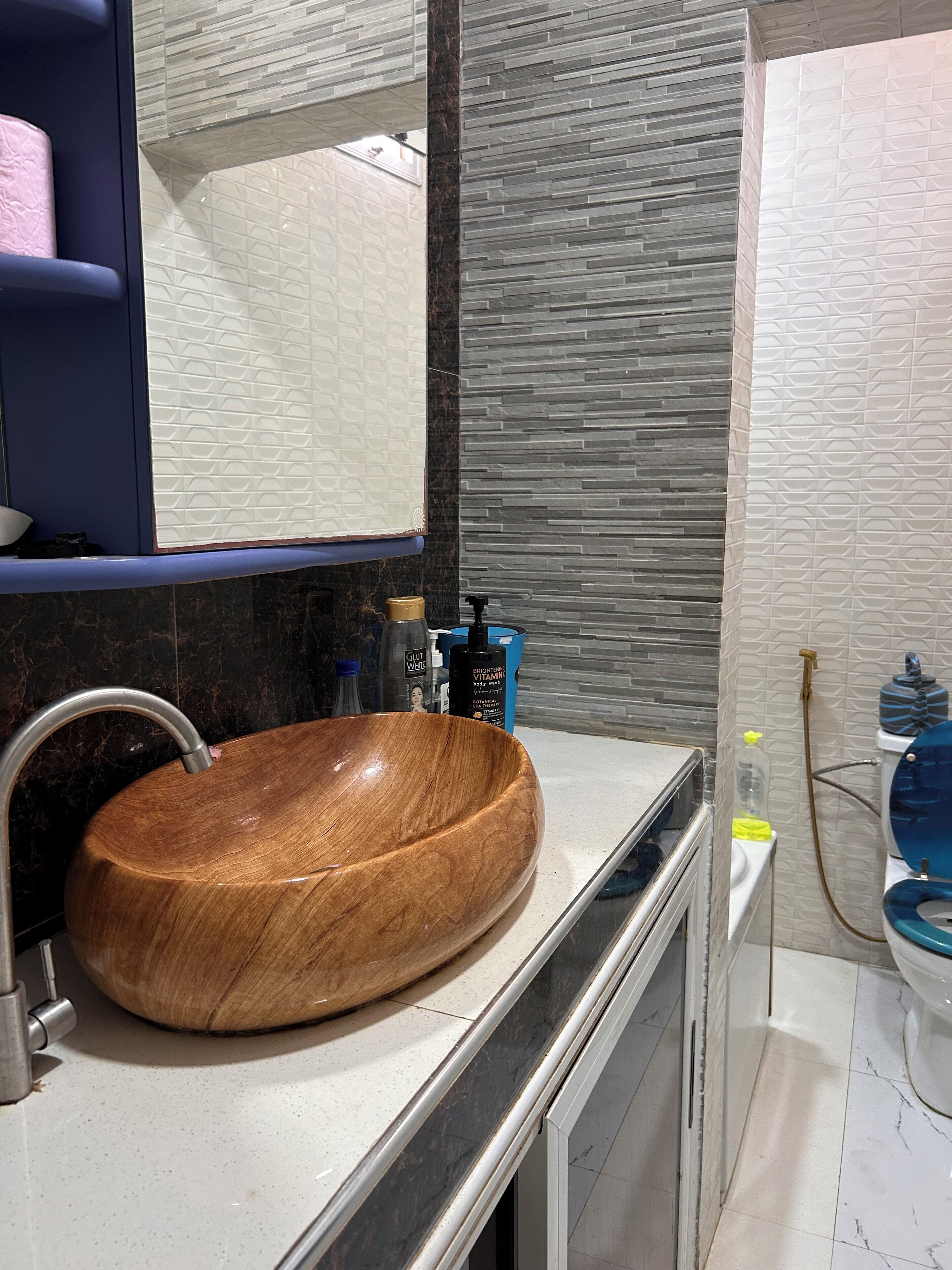 Ein Badezimmer mit einem Holzkosmetikschrank, einem modernen Waschbecken und einem Spiegel.
