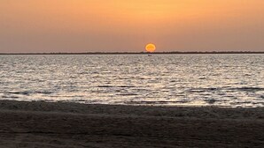 A sunset over a calm body of water with a distant shoreline.