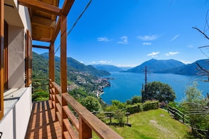 A wooden balcony overlooking a lake with mountains in the background. - Costa Del Fuoco (Bellano)