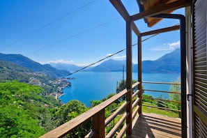 A wooden deck overlooking a lake with mountains in the background. - Costa Del Fuoco (Bellano)