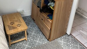 A compact room with a wooden wardrobe, a small wooden table, and a mirror on the wall.