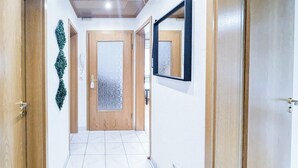 A hallway with wooden doors, a tiled floor, and a mirror on the wall.
