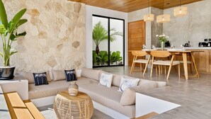 Una sala de estar moderna con una pared de piedra, techo de madera y un comedor con mesa y sillas de madera.