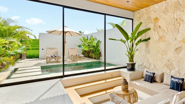 Un interior moderno con un amplio ventanal, una piscina y una zona de estar con sofá y sillones.