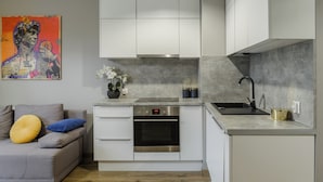 A modern kitchen with white cabinetry, a built-in oven, and a stainless steel sink. - Lumina modern studio with balcony (Lodz)