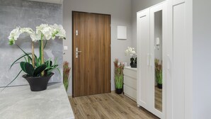 A room with a wooden door, white wardrobe, and potted plants. - Lumina modern studio with balcony (Lodz)