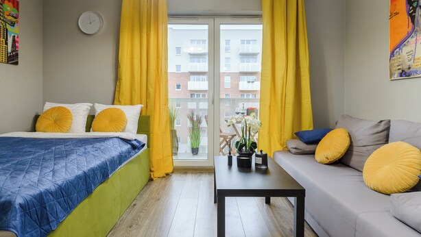 A room with a bed, a sofa, a table, and a window with curtains. - Lumina modern studio with balcony (Lodz)
