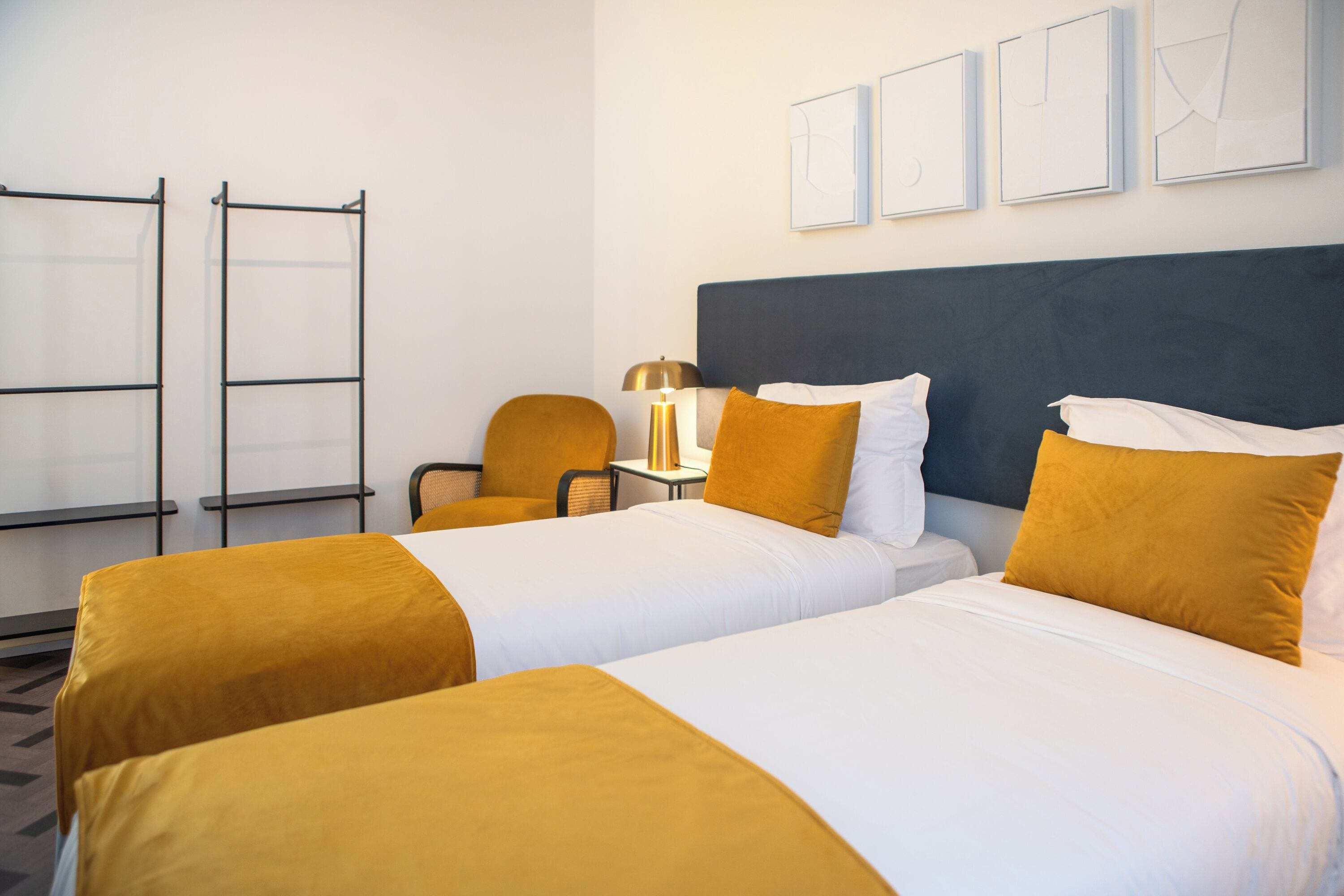 Habitación de hotel con dos camas, un escritorio, una silla y una lámpara.