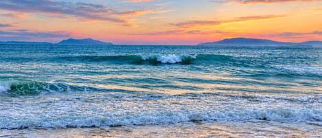 A beach with waves and a sunset.