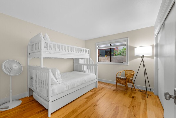 A room with a bunk bed, a standing fan, a wicker chair, and a floor lamp. - 25% Off Oct 22-25 Walk 2 Beach, Rooftop Deck View! (Oxnard)