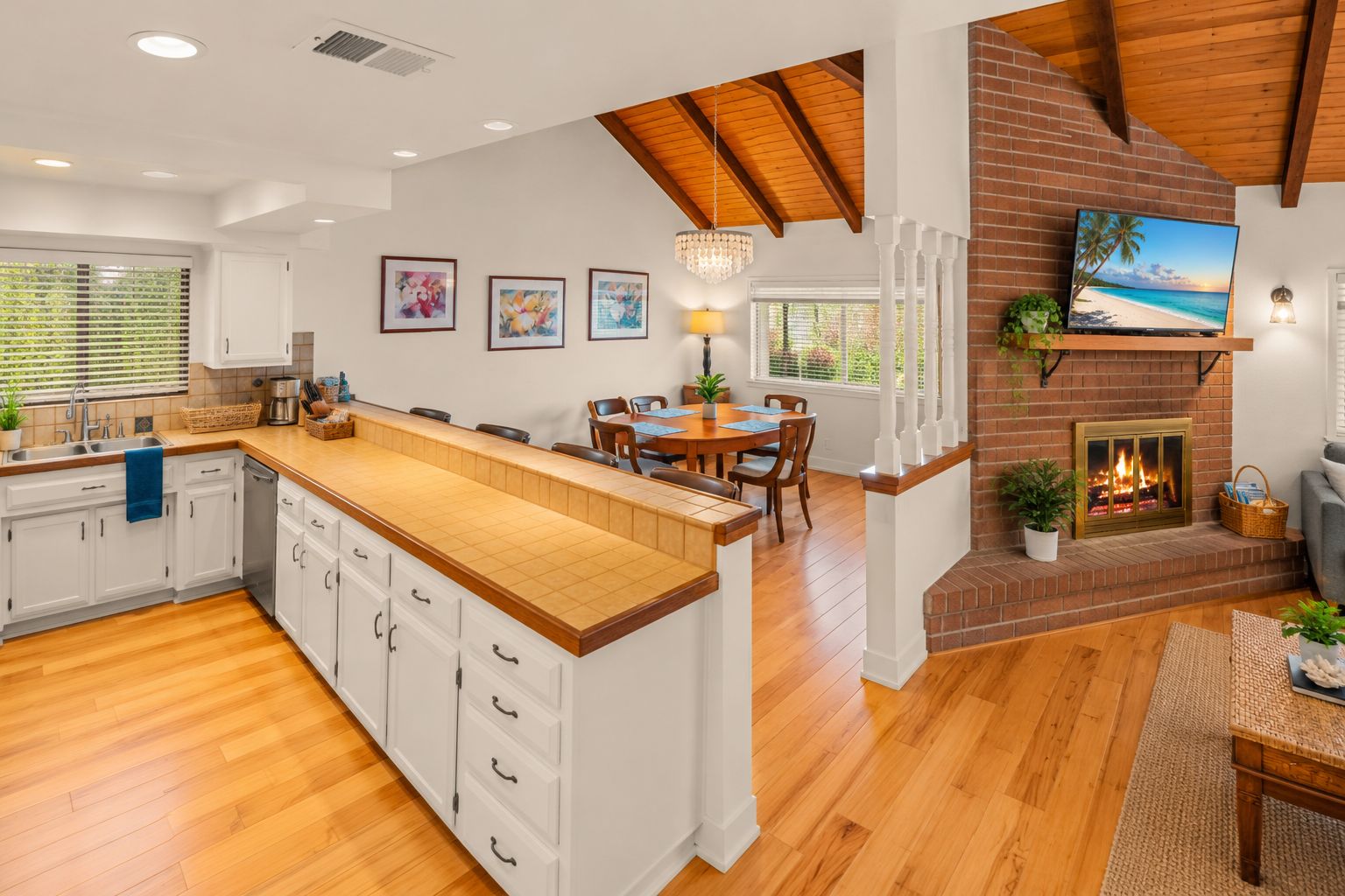 A spacious kitchen with a large island, wooden flooring, and a brick fireplace.