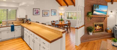 A spacious kitchen with a large island, wooden flooring, and a brick fireplace.