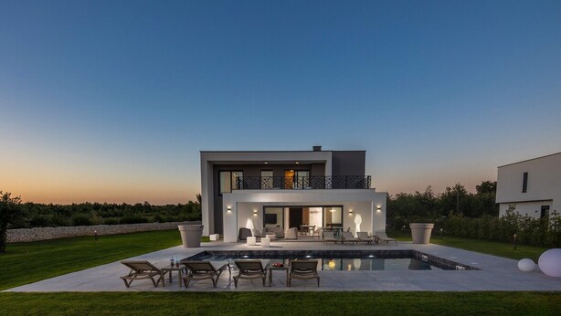 Una casa moderna de dos pisos con piscina y zona de estar al aire libre.