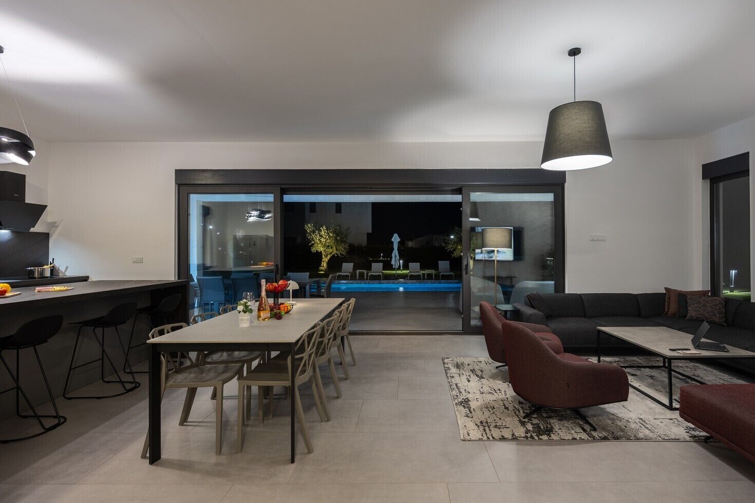 Uma sala de estar moderna com área de jantar, piscina e um sofá.