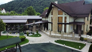 A hotel with a stone facade, multiple windows, and a covered outdoor seating area.