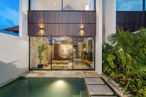 A modern house with a glass front, a pool, and a garden with tropical plants. - Villa Elba - Canggu (Canggu)