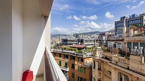 Een balkon met uitzicht op een stadsgezicht, inclusief gebouwen met balkons en een heldere lucht.