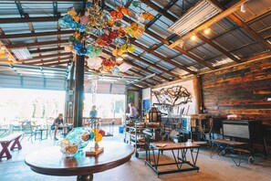 An interior with a rustic wooden wall, a hanging glass ornament, and a table with a vase of flowers.