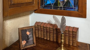 A wooden table with a framed picture, a feather quill, and a row of old books.