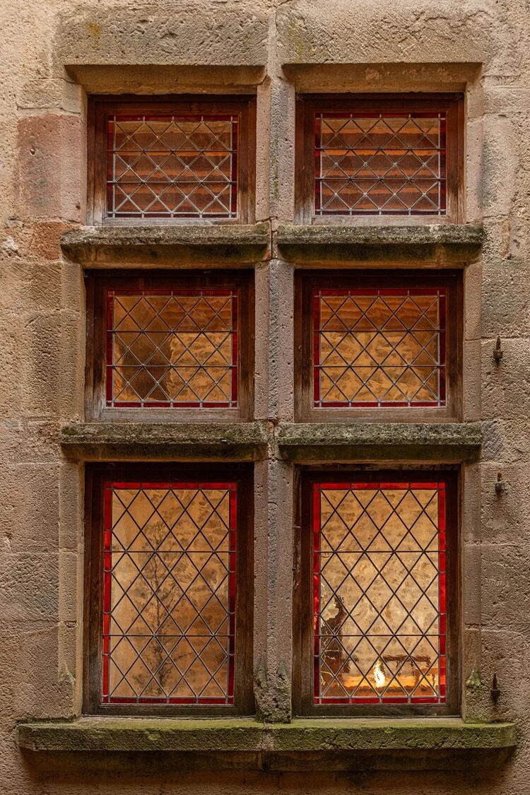 A building facade with four windows, each with a wooden frame and a diamond-patterned grille.