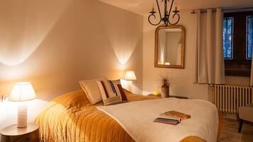 Une chambre à coucher avec un lit, des lampes de chevet, un miroir, un radiateur et une fenêtre avec des rideaux.