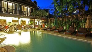 Un área de piscina con sillones de descanso y una zona de comedor.