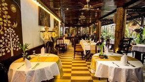 Un restaurante con piso a cuadros, manteles blancos y una variedad de sillas.