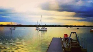 A calm waterfront with a wooden dock extending into the water, surrounded by several boats. - Regnéville sur Mer, gîte de La Sienne, between sea and countryside. (Regnéville-sur-Mer)