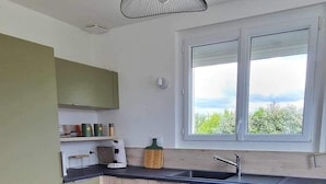 A modern kitchen with a wooden countertop, a built-in sink, and a window overlooking greenery. - Regnéville sur Mer, gîte de La Sienne, between sea and countryside. (Regnéville-sur-Mer)