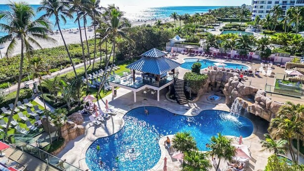 A resort with multiple swimming pools, palm trees, and a beach view. - Oceanfront 2BR at The Alexander · Pools + Beach (Miami)