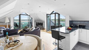 A modern loft-style living space with a dining area, kitchen, and large windows offering a view of the sea. - Beachfront apartment in Rock - Parking - Sea Views (Rock)
