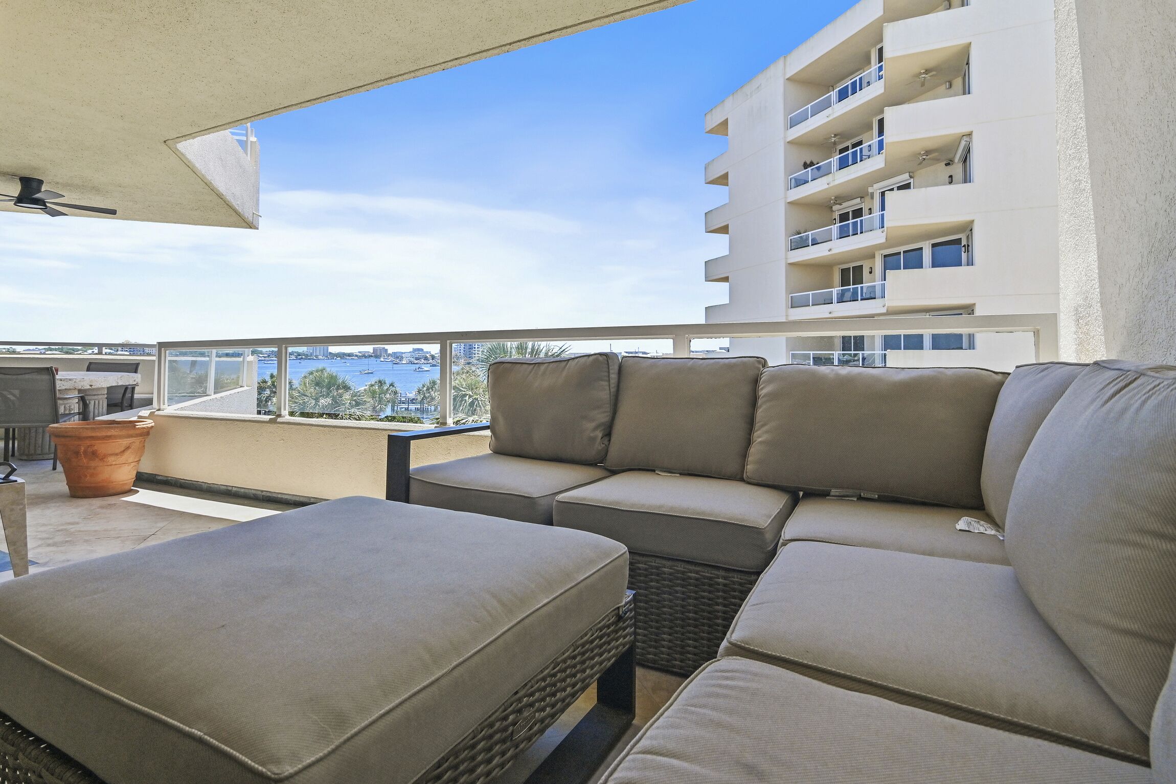 Ein Balkon mit einer Couch und einem Tisch, mit Blick auf eine Stadtlandschaft und Wasser.
