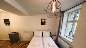 A hotel room with a bed, a radiator, a window, and a hanging light fixture. - Central charming apartment in the old town center (Bayreuth)