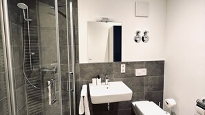 A modern bathroom with a glass-enclosed shower, a sink, and a toilet. - Central charming apartment in the old town center (Bayreuth)