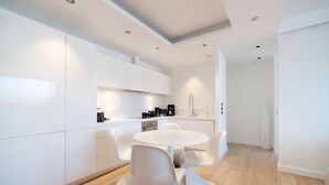 Une cuisine moderne avec des meubles blancs, une table de salle à manger ronde et des chaises blanches.