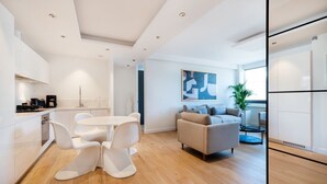 Une cuisine moderne avec des meubles blancs et un coin repas comprenant une table ronde et des chaises blanches.