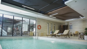 Ein Hallenbad mit Liegestühlen und einem Rettungsreifen an der Wand.