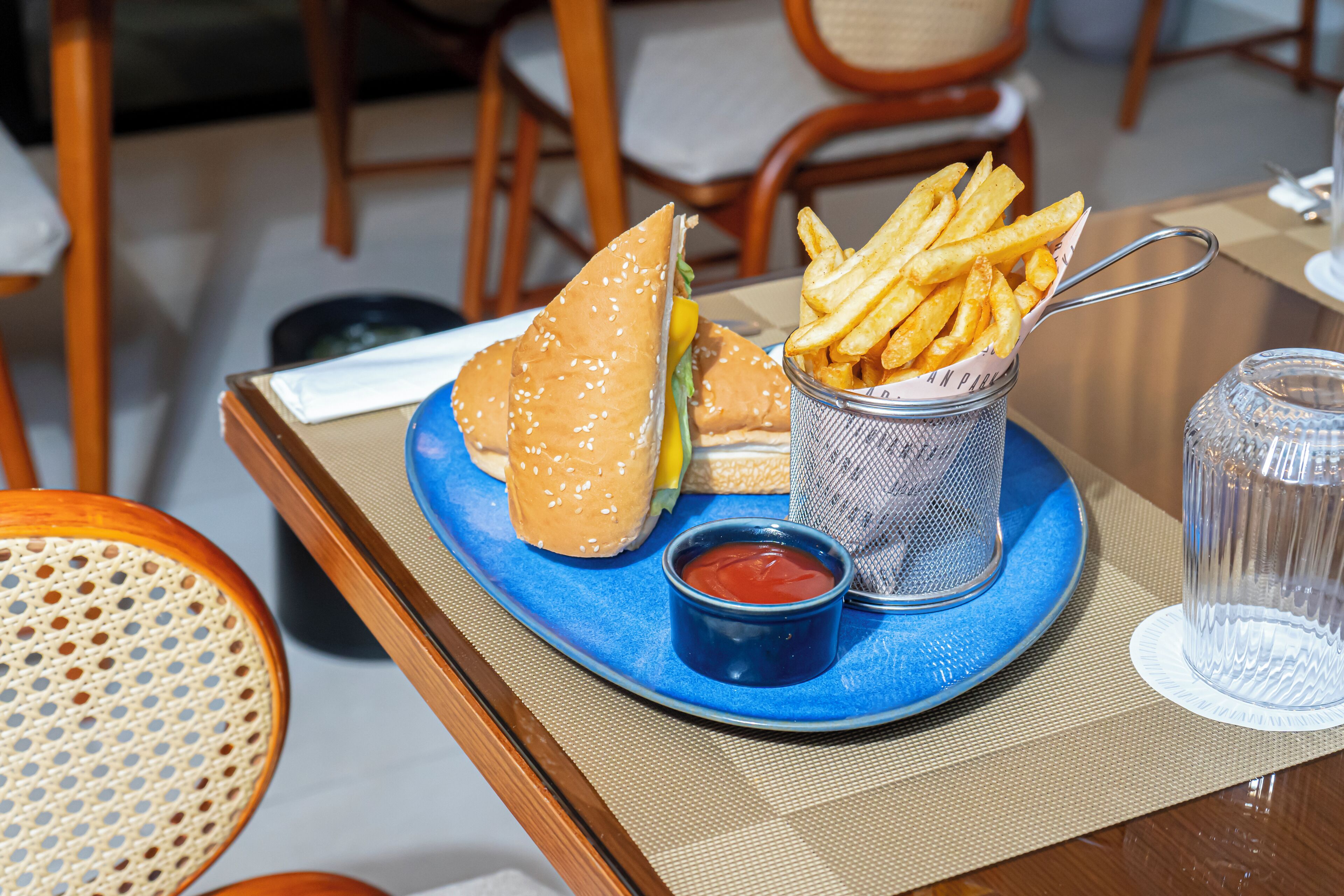 A tray with a hamburger, French fries, and a small cup of ketchup on a blue tray.