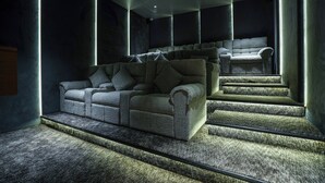 Ein moderner Kinoraum mit einer bequemen Couch und einer Treppe.