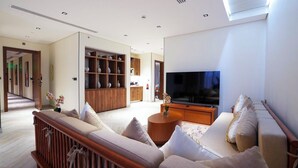 Ein modernes Wohnzimmer mit einer Sofagarnitur, einem Fernseher und einer Holzkommode mit Regalen.