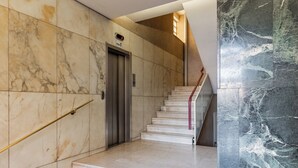 Una escalera de mármol con barandilla que da a un ascensor.